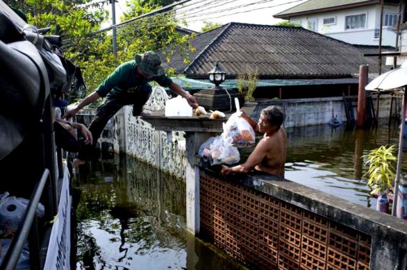Food distribution by the Thai Army to the victims of the floods. People who have stayed in their submerged houses are getting little access to food as they have to reach the distributions points. A man reach over the wall of his house to collect the food bags.